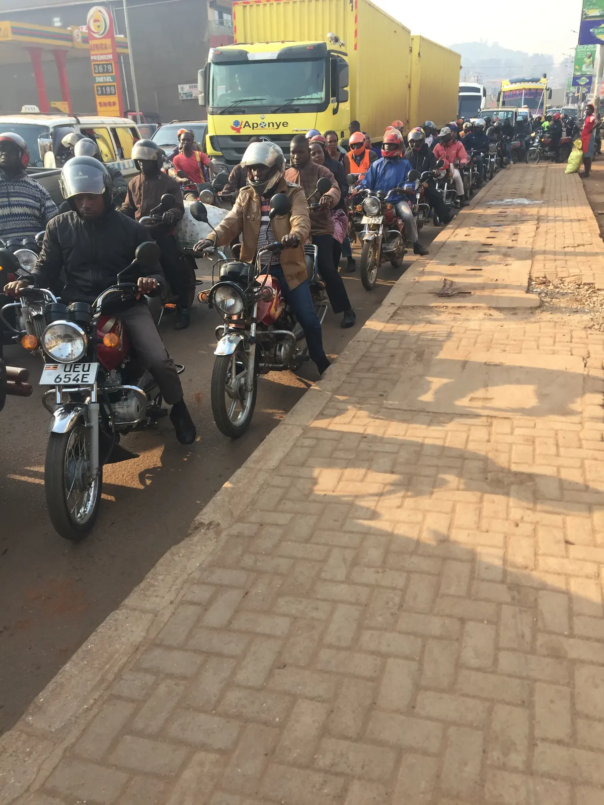 A car and a boda-boda motorcycle on a Ugandan street